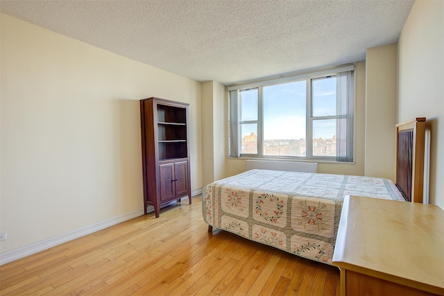 bedroom featuring light wood finished floors, baseboards, and a textured ceiling