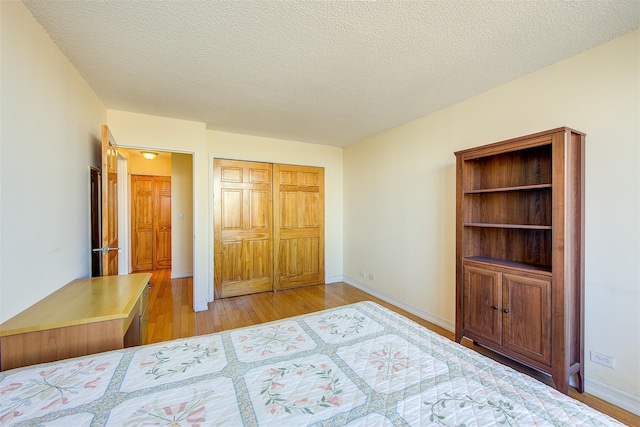 unfurnished bedroom with a textured ceiling, a closet, baseboards, and light wood-style floors