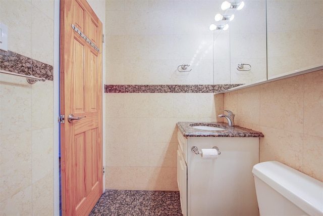 bathroom featuring toilet, tile walls, and vanity