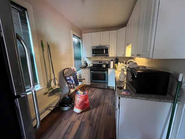 kitchen featuring a heating unit, white cabinetry, stainless steel appliances, and dark wood-type flooring