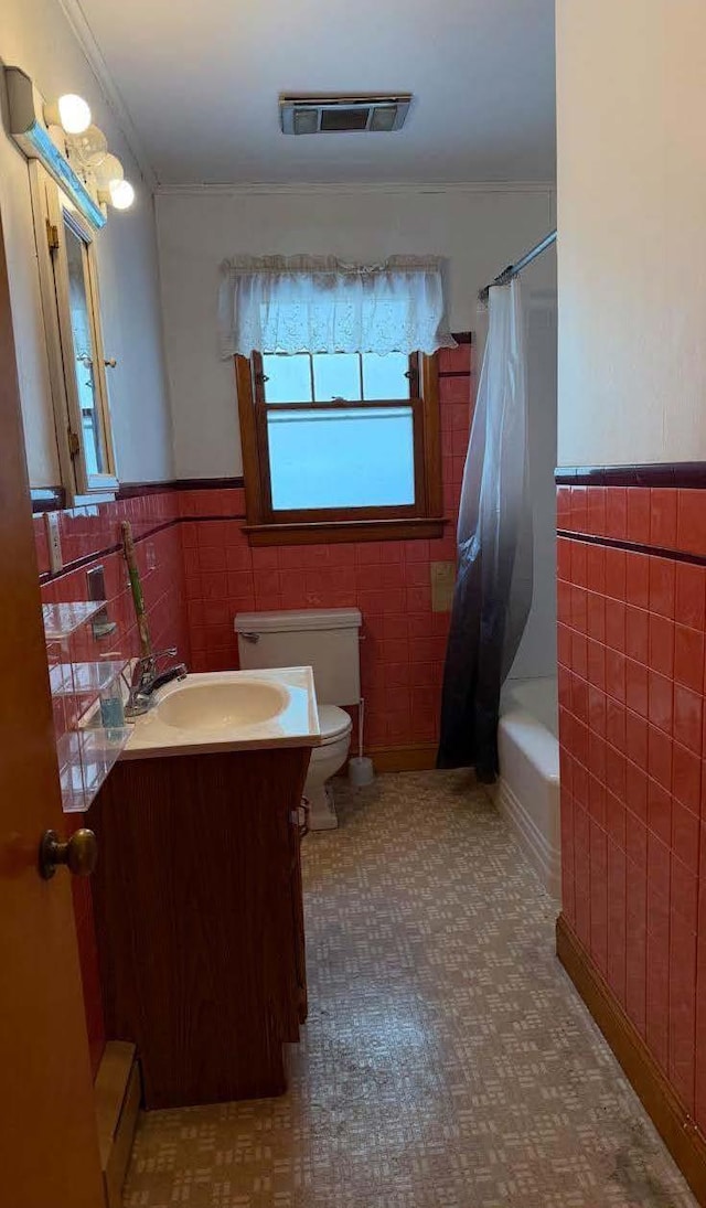 bathroom with toilet, vanity, visible vents, tile walls, and wainscoting