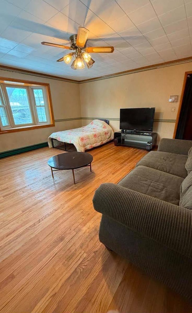 living area featuring ornamental molding, baseboard heating, ceiling fan, and light wood finished floors