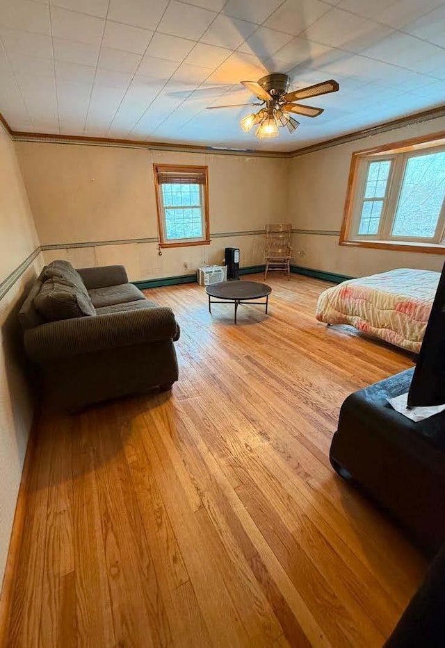 bedroom featuring crown molding, a baseboard radiator, a ceiling fan, light wood-type flooring, and baseboards