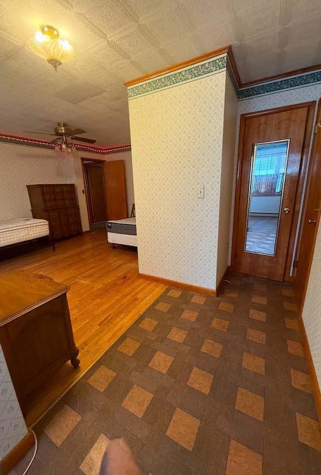 corridor with wallpapered walls, an ornate ceiling, and baseboards