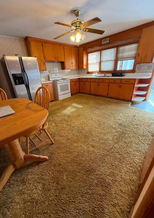 kitchen featuring stainless steel refrigerator with ice dispenser, light countertops, electric range, brown cabinetry, and a ceiling fan