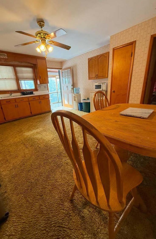 dining area featuring ceiling fan, carpet floors, and wallpapered walls