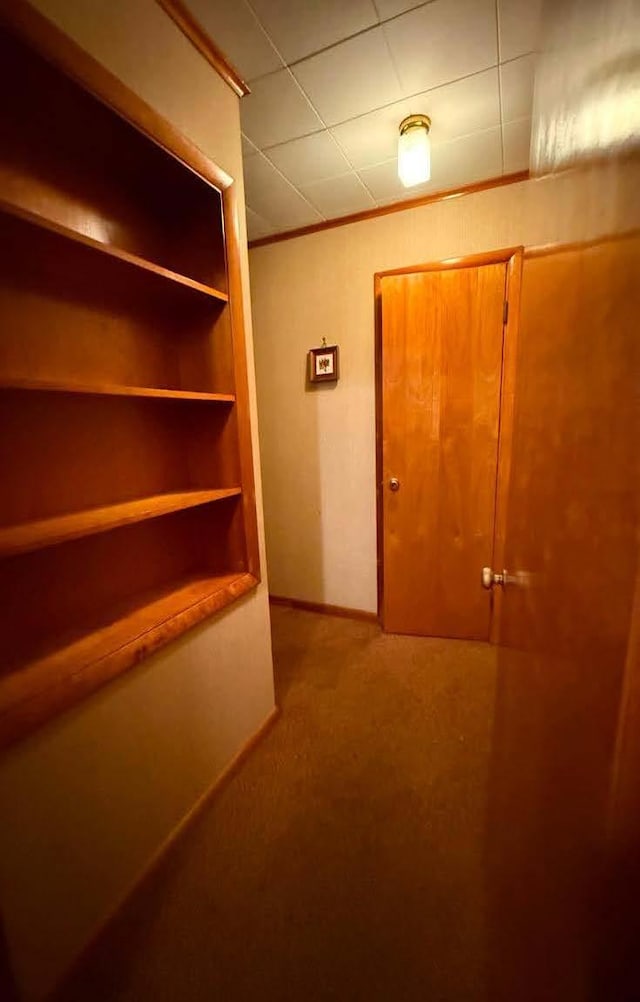 hallway featuring carpet floors, baseboards, and crown molding