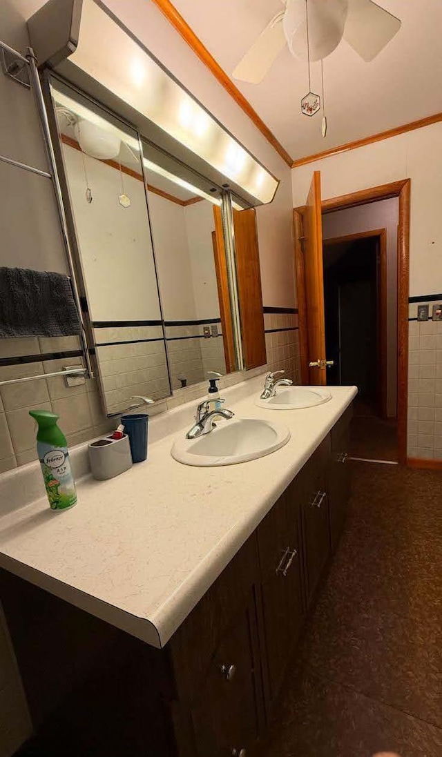 bathroom with double vanity, tile walls, a sink, and ornamental molding