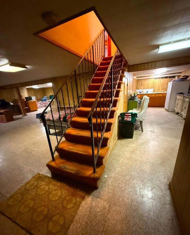 interior space featuring tile patterned floors, wood walls, and stairs