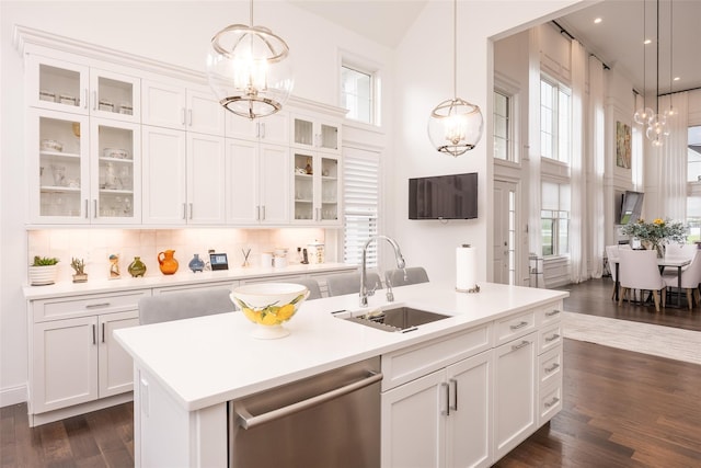 kitchen featuring pendant lighting, light countertops, stainless steel dishwasher, white cabinets, and a sink