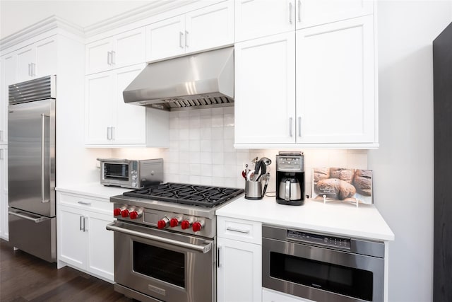 kitchen featuring a toaster, built in appliances, ventilation hood, light countertops, and white cabinetry