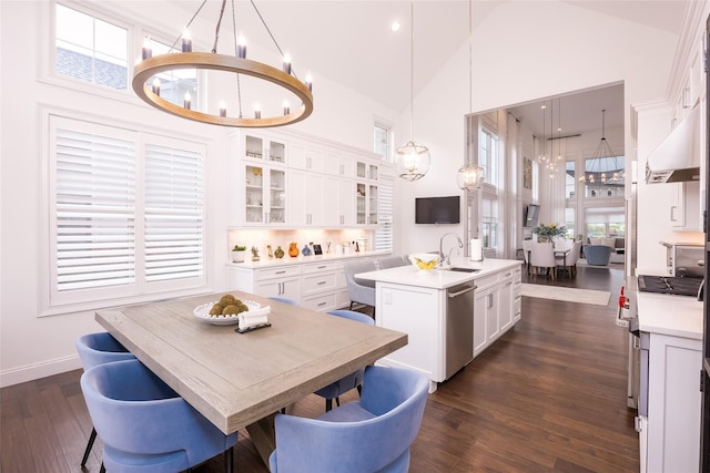 kitchen featuring pendant lighting, light countertops, glass insert cabinets, white cabinetry, and an island with sink