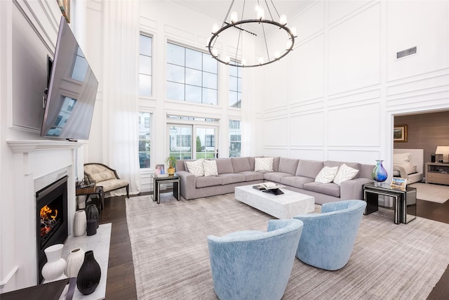 living area with a fireplace with flush hearth, wood finished floors, visible vents, and a decorative wall