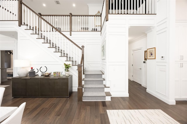 stairway with ornamental molding, a decorative wall, wood finished floors, and recessed lighting