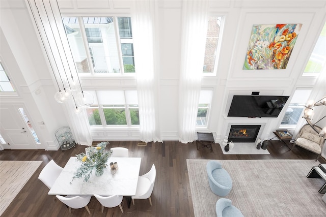 living room with dark wood-style flooring, a fireplace with flush hearth, and a decorative wall