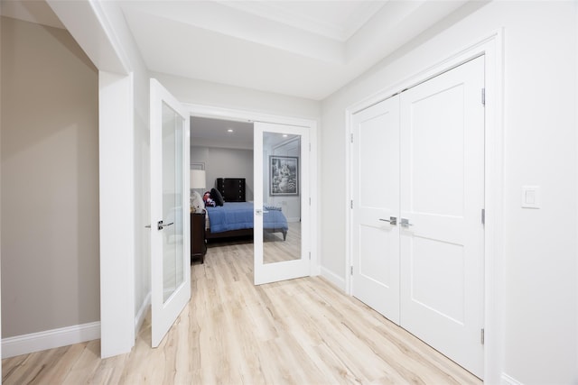 corridor with french doors, light wood-type flooring, and baseboards