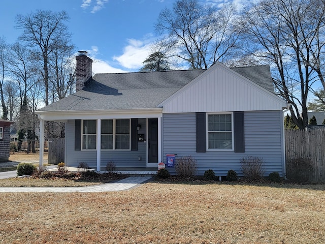 view of front of property with a shingled roof, a front yard, fence, and a chimney