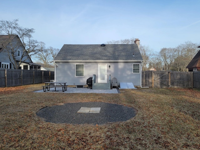 back of house with a patio, a fenced backyard, a yard, a gate, and a chimney