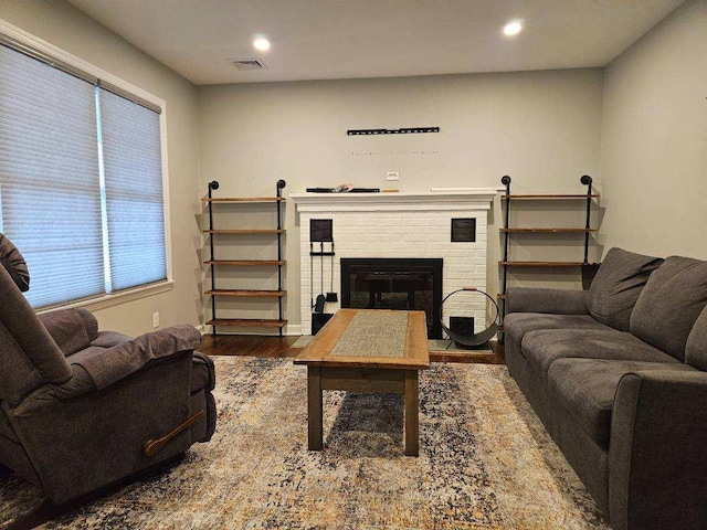 living area with a fireplace, wood finished floors, visible vents, and recessed lighting