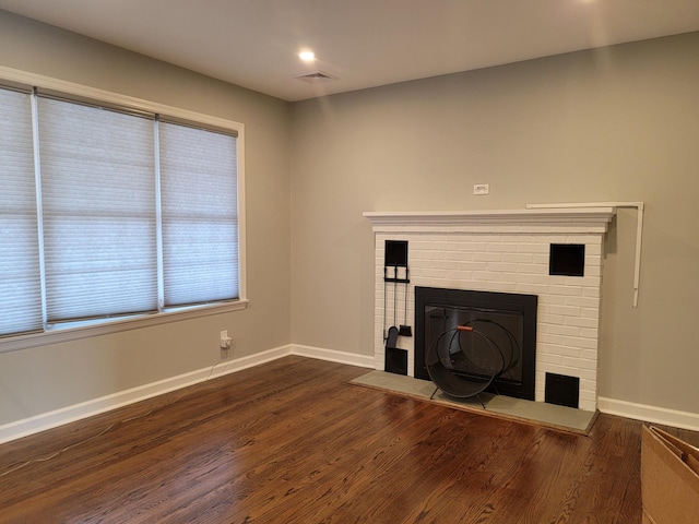 unfurnished living room featuring dark wood-type flooring, a fireplace, visible vents, and baseboards