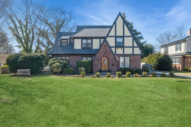 tudor-style house featuring a front yard, brick siding, and stucco siding