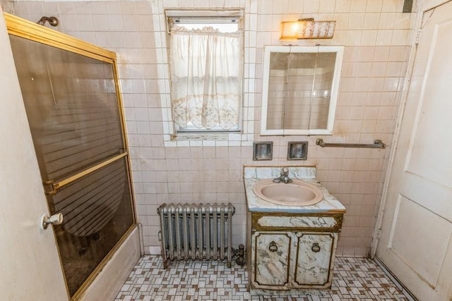 5130 47th St, Woodside, NY 11377 - bathroom with combined bath / shower with glass door, radiator, tile walls, and vanity