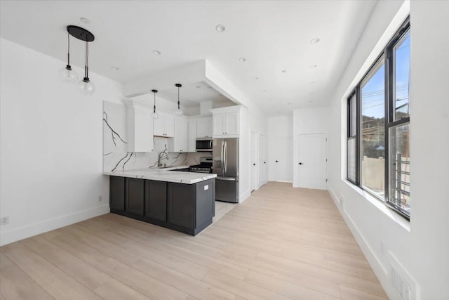 kitchen featuring decorative backsplash, light stone countertops, stainless steel appliances, light wood-style floors, and white cabinetry