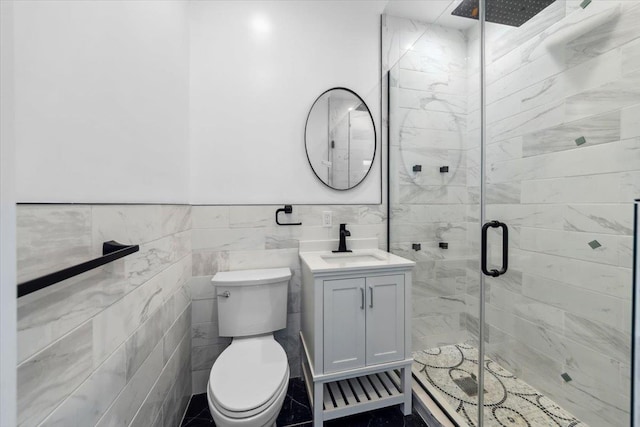 bathroom featuring tile walls, toilet, wainscoting, a shower stall, and vanity