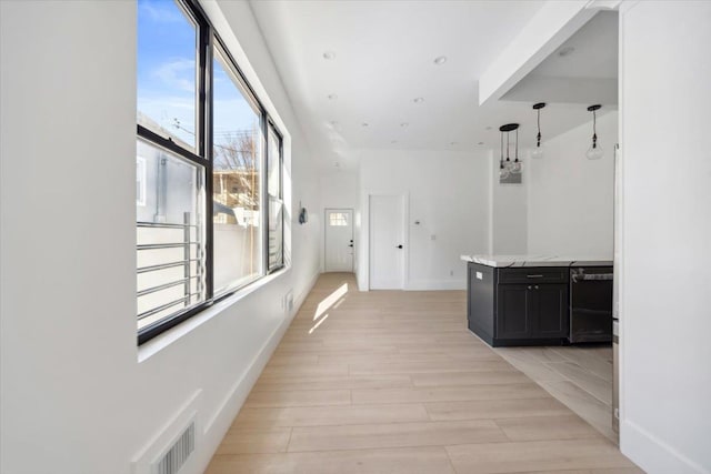 hallway with light wood finished floors, baseboards, visible vents, and recessed lighting