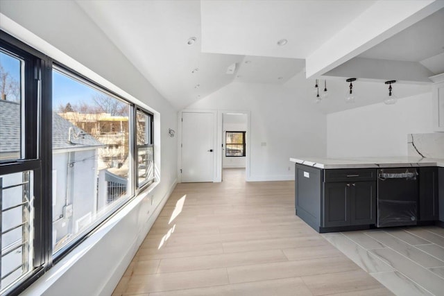 kitchen with baseboards, vaulted ceiling, light countertops, black dishwasher, and light wood-style floors