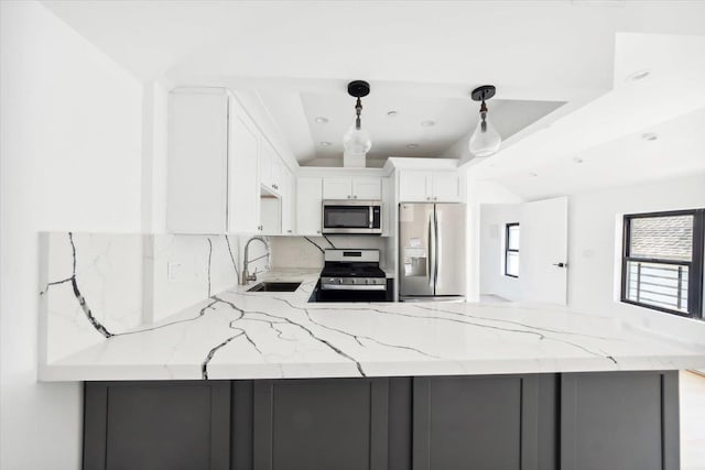 kitchen with stainless steel appliances, a peninsula, a sink, white cabinetry, and light stone countertops