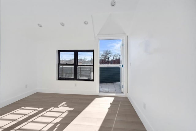 unfurnished room featuring dark wood-style floors, lofted ceiling, and baseboards