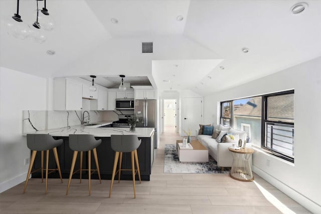 953 Tilden St, Bronx, NY 10469 - kitchen featuring a sink, stainless steel appliances, a peninsula, lofted ceiling, and visible vents