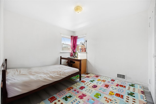 bedroom with visible vents, baseboards, and wood finished floors