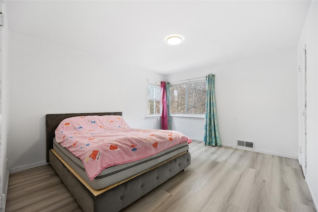 bedroom with light wood-style floors, visible vents, and baseboards