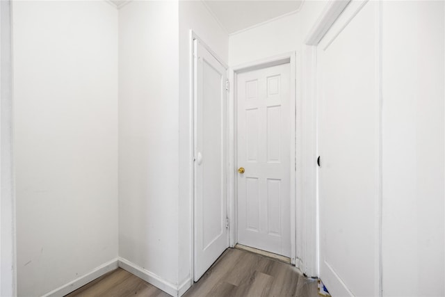 hall featuring crown molding, baseboards, and wood finished floors