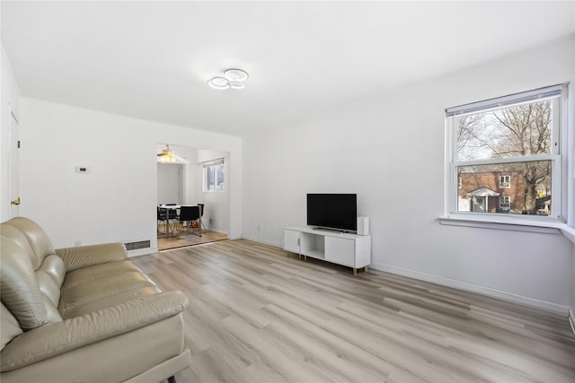 living area with visible vents, light wood-style flooring, and baseboards