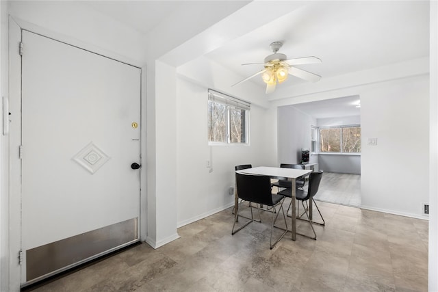 dining space with ceiling fan and baseboards