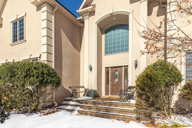 snow covered property entrance featuring stucco siding