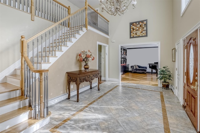 foyer entrance with a chandelier, baseboards, a high ceiling, and stairs