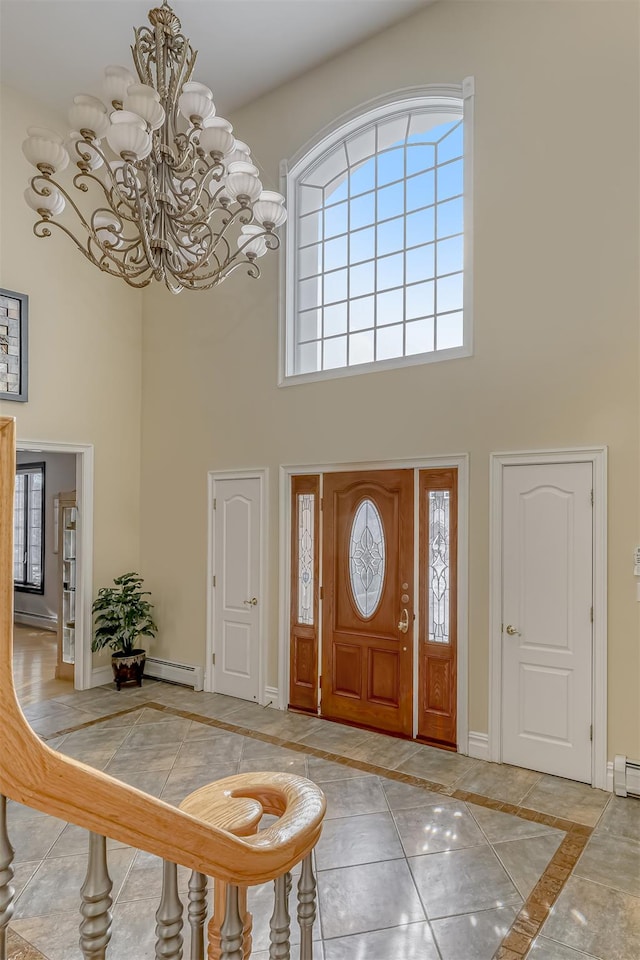 entrance foyer with baseboards, a towering ceiling, baseboard heating, and a notable chandelier