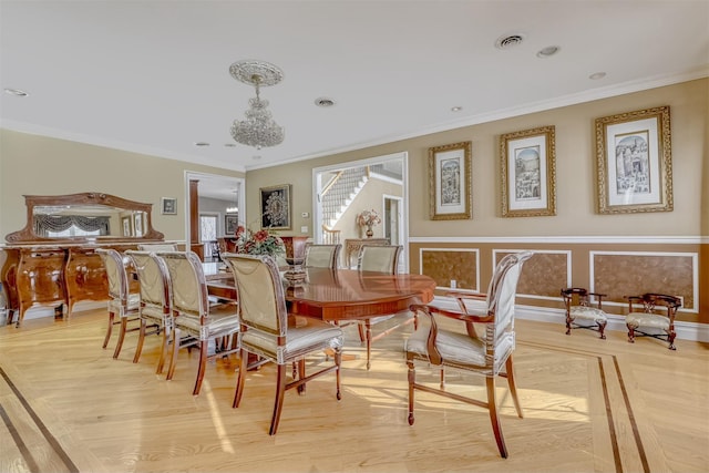 dining area with light wood-type flooring, visible vents, and ornamental molding