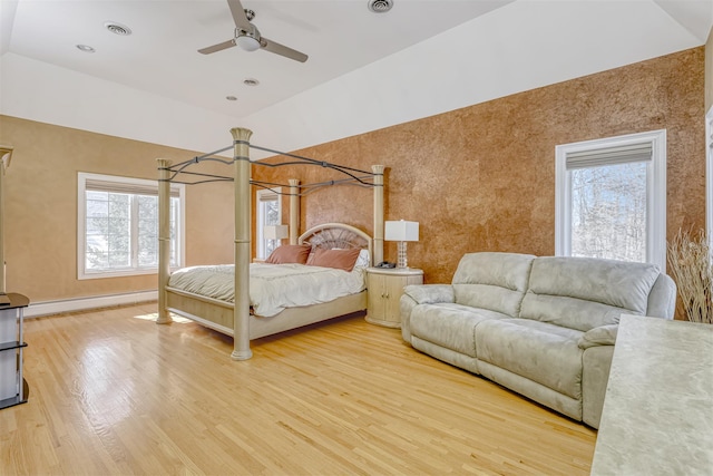 bedroom with wood finished floors, visible vents, baseboard heating, and multiple windows