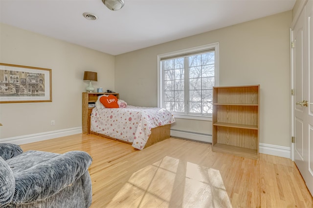 bedroom with baseboards, wood finished floors, and baseboard heating
