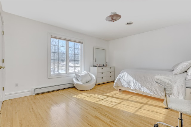 bedroom with wood finished floors, visible vents, and baseboard heating
