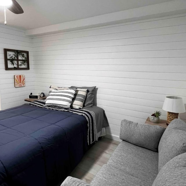 bedroom with wooden walls, light wood-style flooring, and a ceiling fan