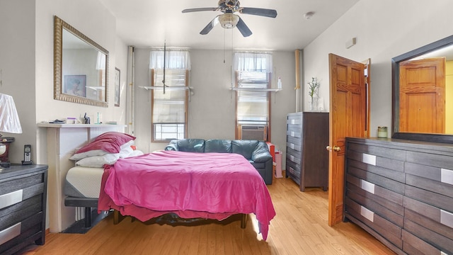 bedroom featuring a ceiling fan, light wood-type flooring, and cooling unit