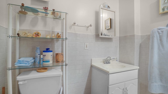 bathroom featuring tile walls, wainscoting, vanity, and toilet