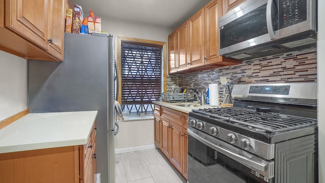 kitchen with stainless steel appliances, brown cabinetry, light countertops, and backsplash