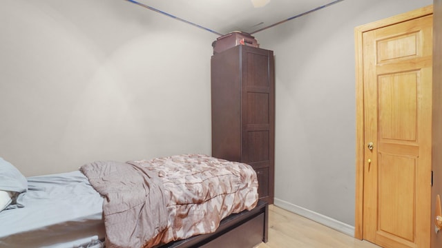 bedroom with light wood-style flooring, baseboards, and a ceiling fan